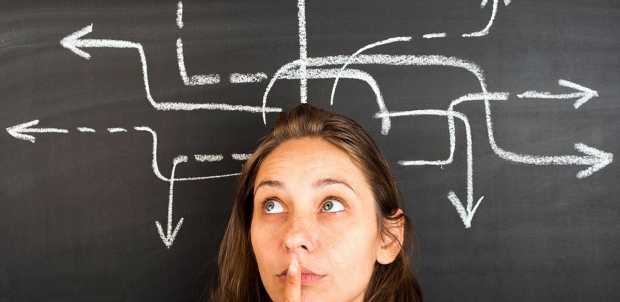 Person thinking below chalkboard arrows pointing in many directions, illustrating decision fatigue.