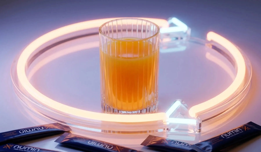 Decision fatigue drink in a glass encircled by a glowing neon brain outline with Numin stick packs on a reflective surface.