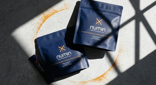 Two navy Numin decision fatigue supplement pouches on concrete with orange powder arc.