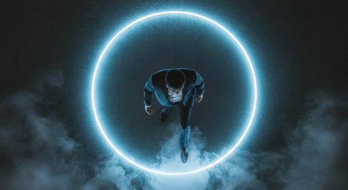 Overhead view of a suited person standing inside a glowing blue neon circle amid mist.