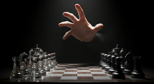 Hand reaching over a chessboard of glass and black pieces, illustrating decision-making strategy.