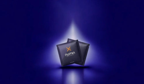Brain drink sachets by Numin featured under a spotlight on a dark blue background.