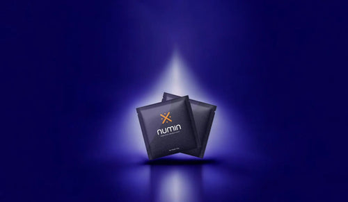 Mental clarity supplements Numin packets illuminated by a focused beam of light against a deep blue background symbolizing enhanced cognition