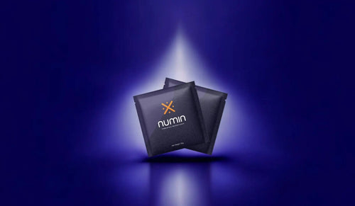 Natural supplements for brain fog in sleek Numin sachets highlighted by a dramatic spotlight on a deep blue background.