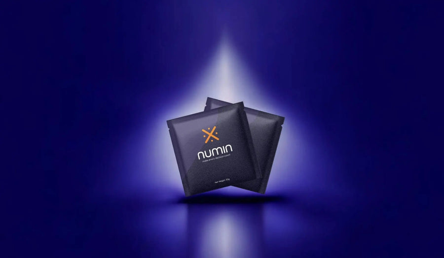 Natural supplements for brain fog in sleek Numin sachets highlighted by a dramatic spotlight on a deep blue background.
