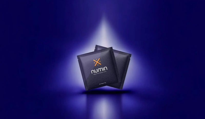 Natural supplements for brain fog in sleek Numin sachets highlighted by a dramatic spotlight on a deep blue background.