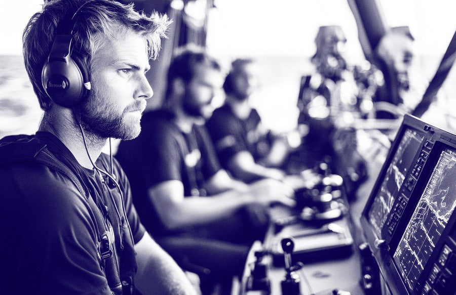 Researcher with headphones analyzing data on computer screen in black and white photo