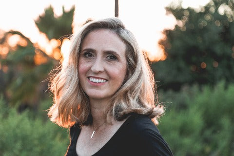 Smiling blonde woman outdoors during golden hour, representing a podcast host for decision-making content