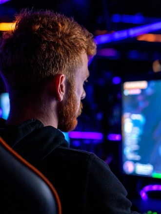 Person with headset viewing colorful gaming setup with blue and purple LED lighting in dark room