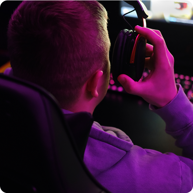 Gamer wearing gaming headset with purple lighting in dark room