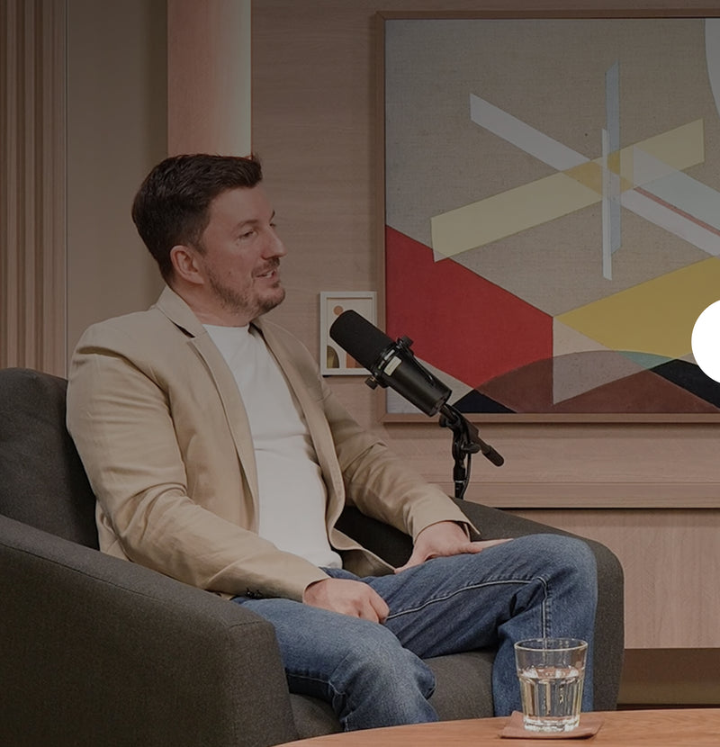 Man in beige blazer speaking into microphone during podcast interview about decision fatigue and mental clarity