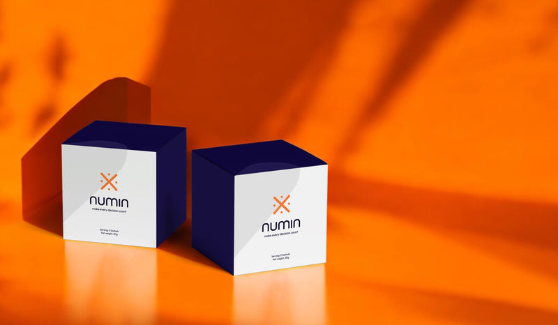 Two navy and white Numin supplement boxes on a bright orange background.